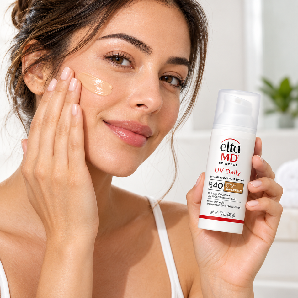 Woman applying EltaMD UV Daily Tinted SPF 40 Face Sunscreen with hyaluronic acid to her cheek while holding the 1.7 oz sunscreen bottle during her daily skincare routine.