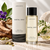 Lake & Skye Santal Gray Body Oil 3.4 oz (100 ml) luxury product presentation with sandalwood, violet flowers, cardamom, and elegant natural stone styling.